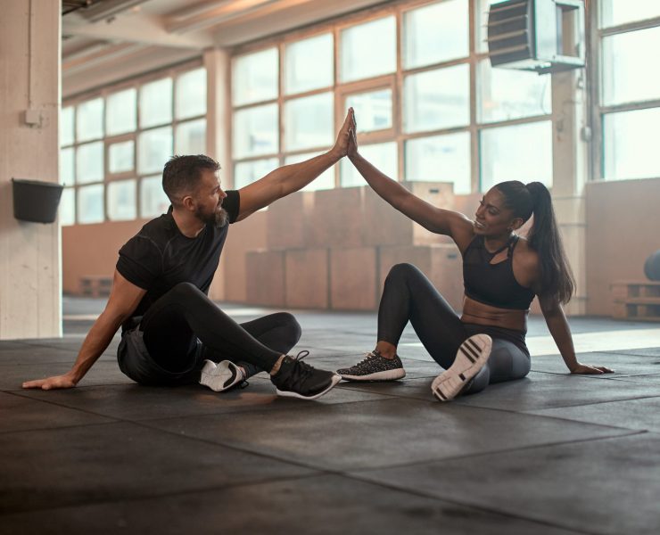 Workout partners high-fiving at the gym